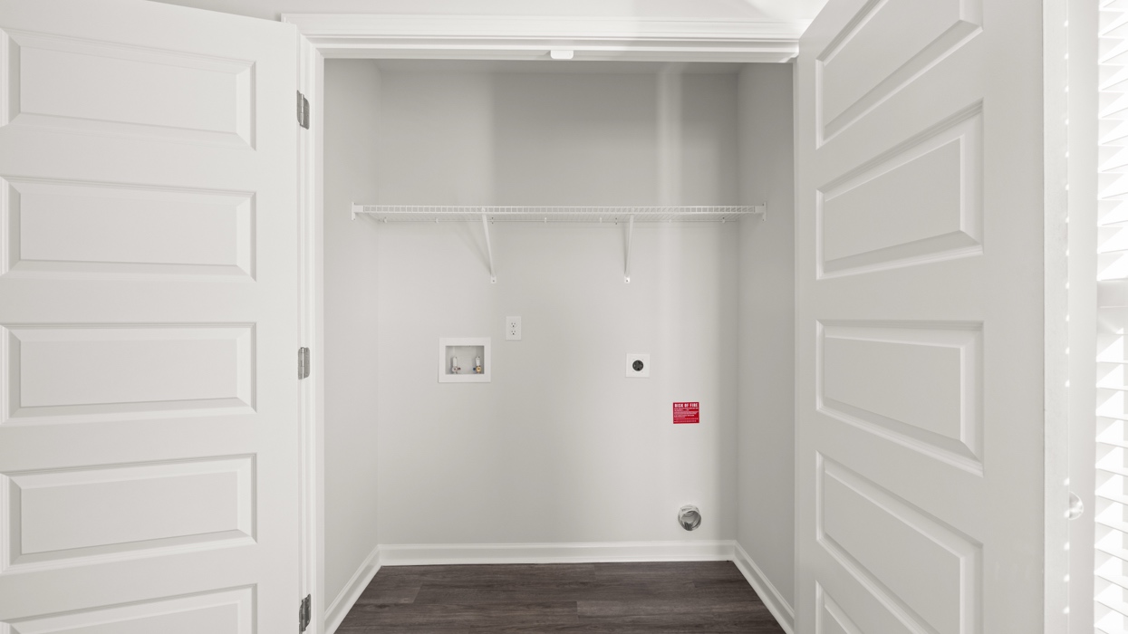 Laundry room with appliance connections and shelving.