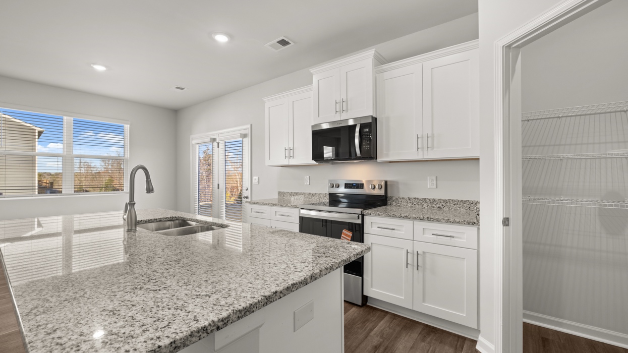 Bright kitchen with center island, stainless appliances, & granite counters