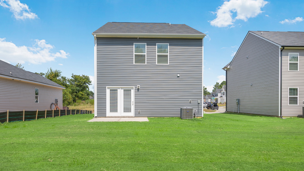 Rear of two story home with back patio and lush green lawn