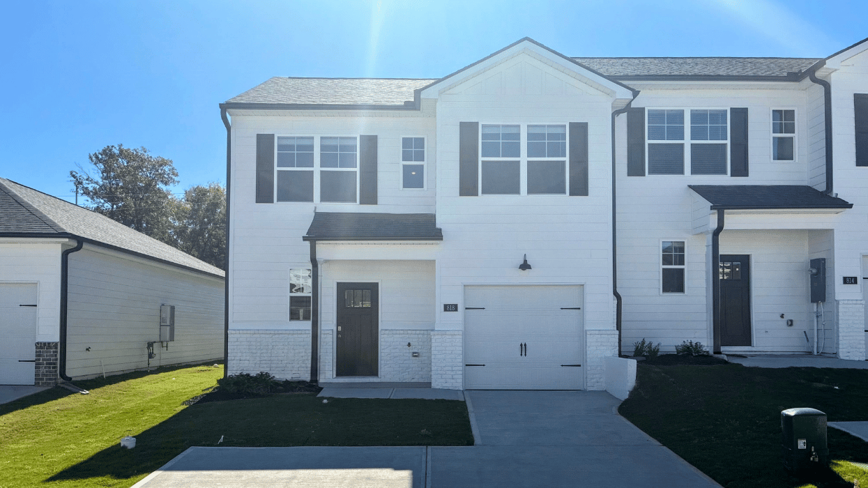 Two-story white townhome end unit with a one car garage.
