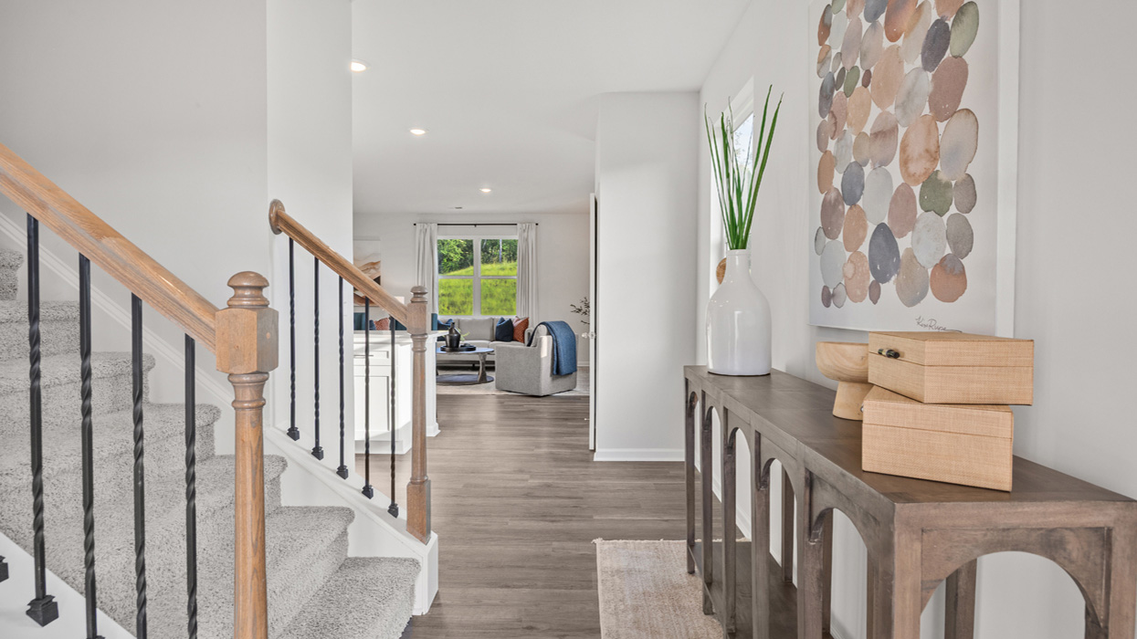 Front door opens to entryway with stairwell on left and living room at far end