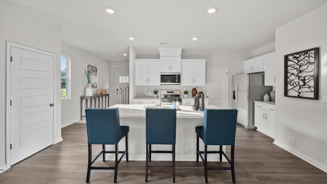 Bright and modern kitchen with tile backsplash, quartz countertops, stainless appliances, and large center island with countertop bar