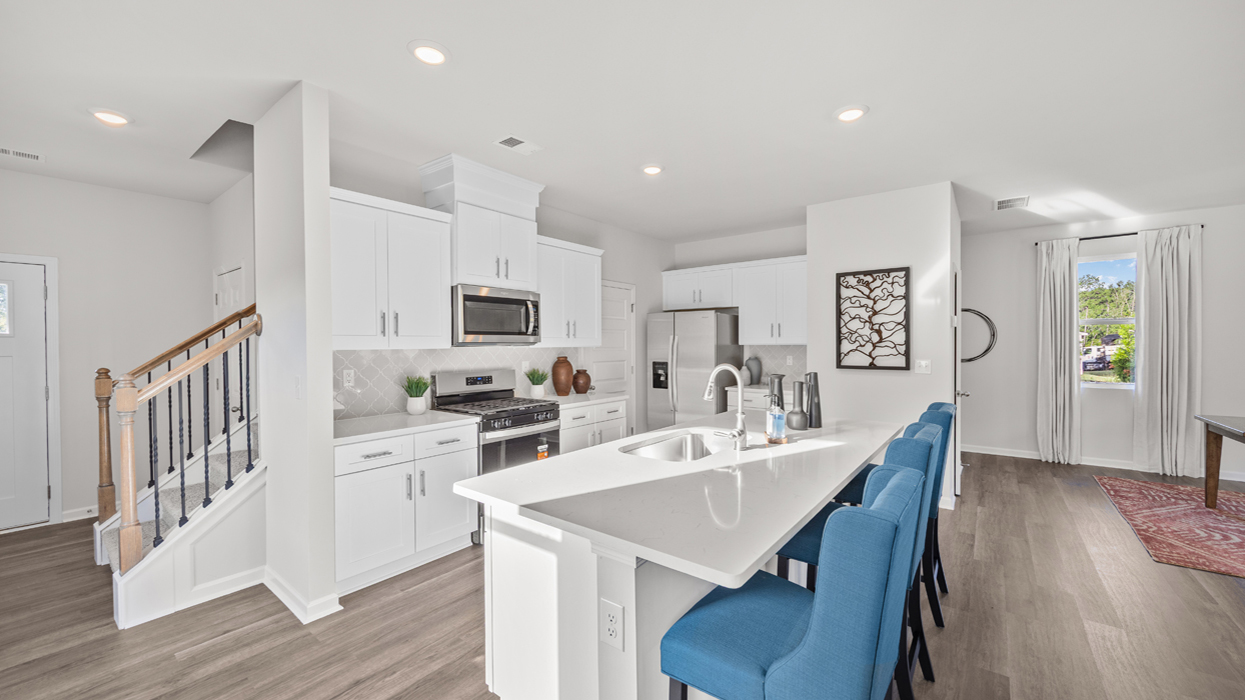 Bright and modern kitchen with tile backsplash, quartz countertops, stainless appliances, and large center island with countertop bar