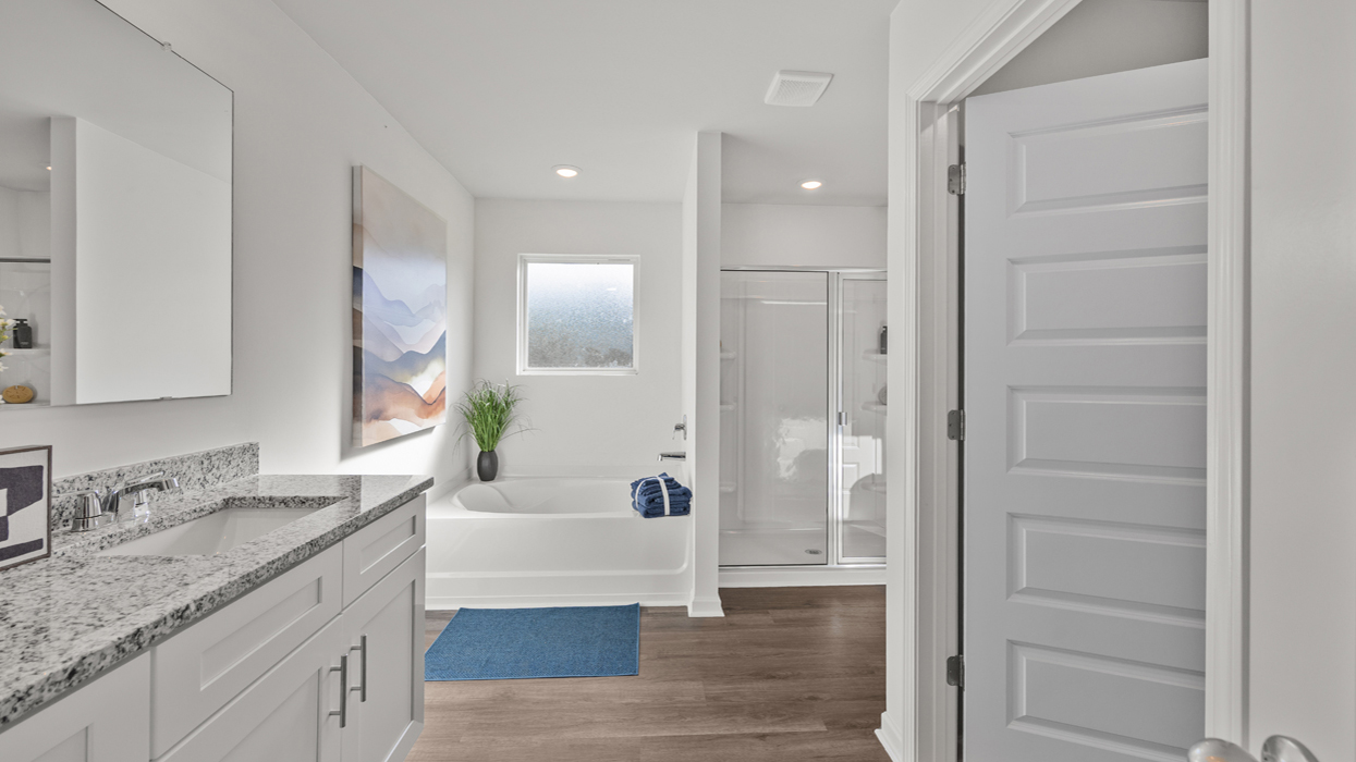 Primary bathroom with garden tub, shower with glass door, double vanity, and water closet with commode