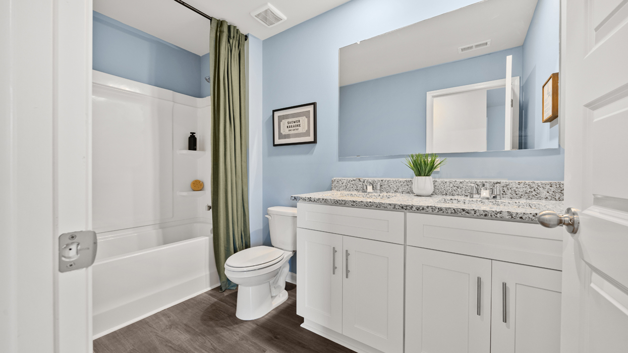 Guest bath upstairs with double vanity, commode, and tub/shower combo.
