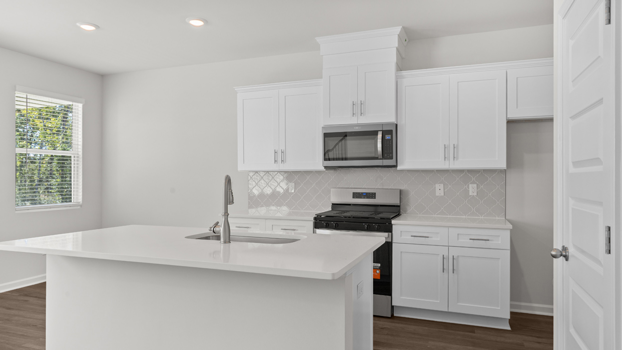 Modern kitchen with quartz countertops, shaker cabinets, tile backsplash, and stainless gas appliances with large center island