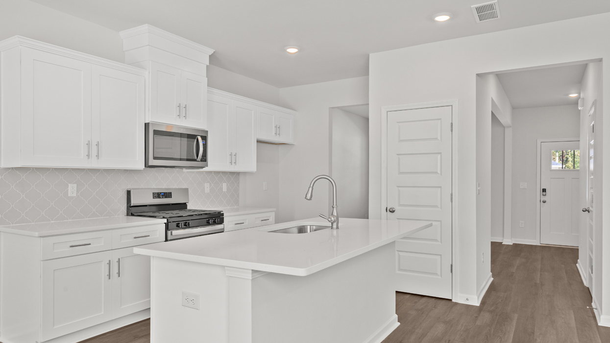 Modern kitchen with quartz countertops, shaker cabinets, tile backsplash, and stainless gas appliances with large center island