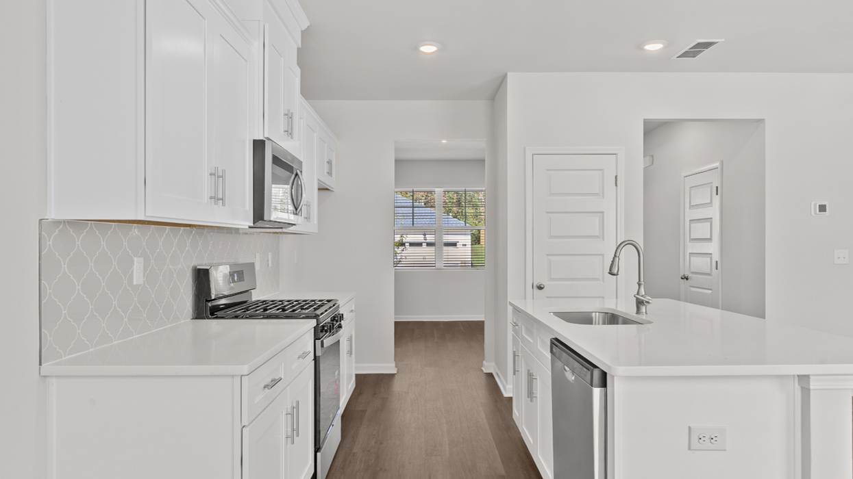 Modern kitchen with quartz countertops, shaker cabinets, tile backsplash, and stainless gas appliances with large center island