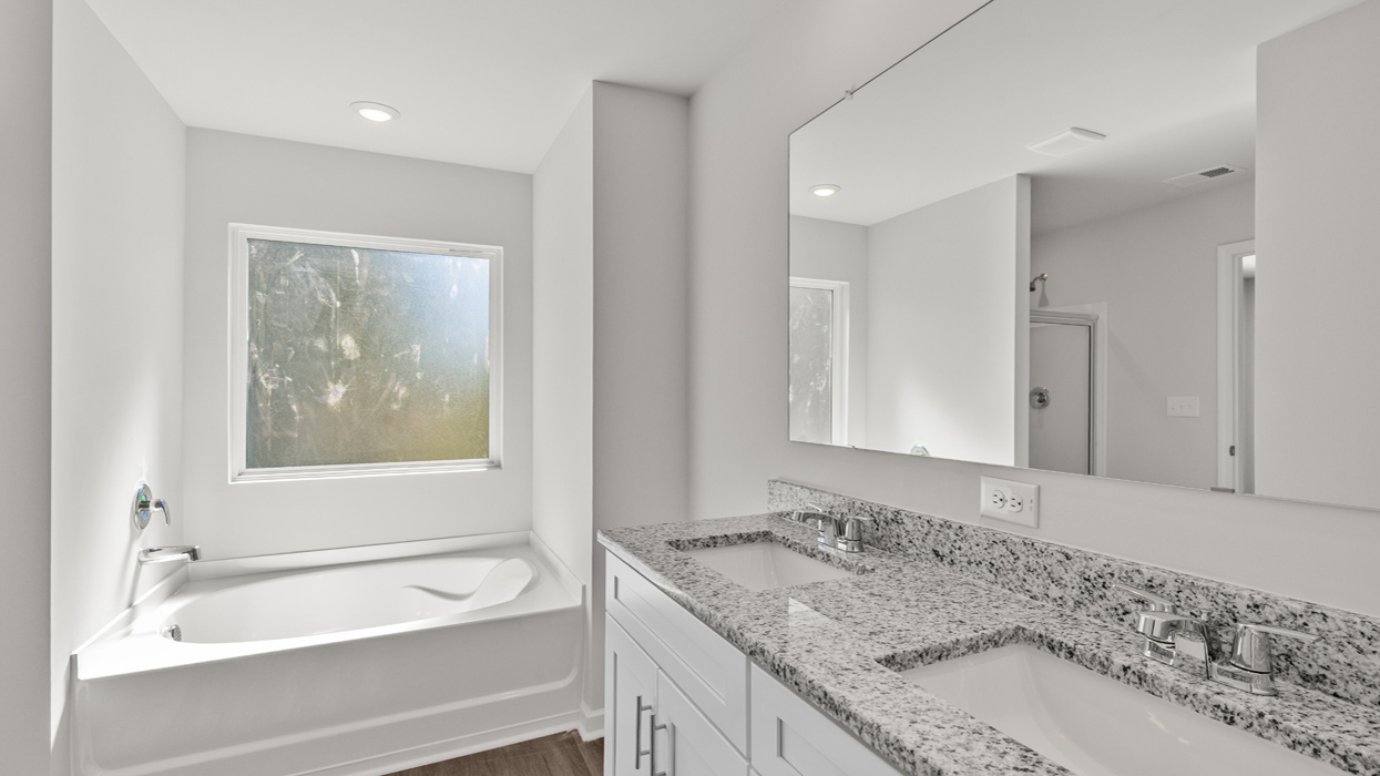 Primary bath with double vanity, garden tub, and shower with glass door.