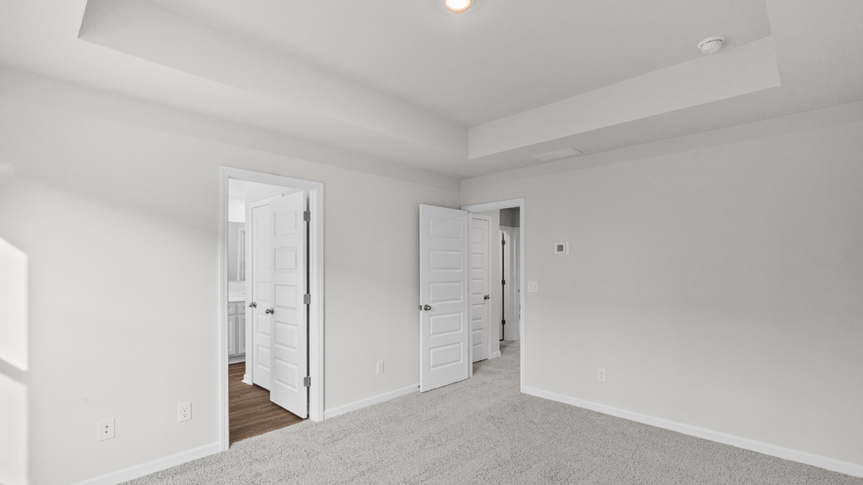 Primary bedroom with tray ceilings and en suite bath.