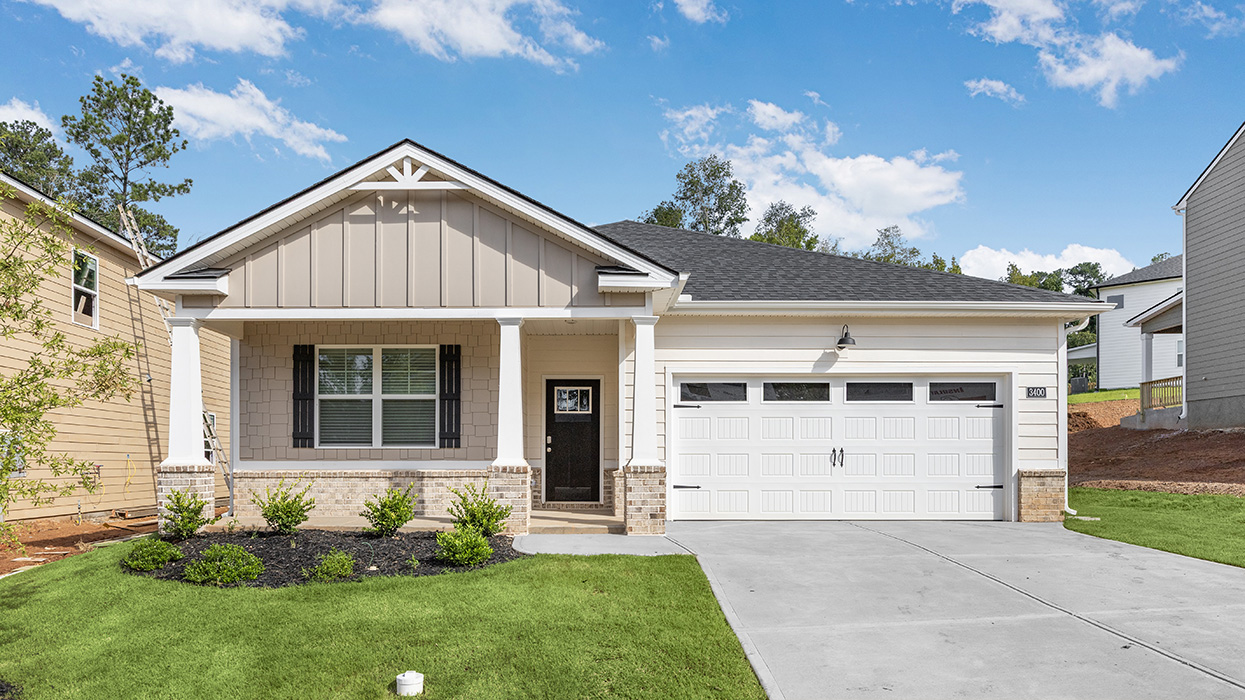 Single story ranch home in cream with large covered front porch and two car garage