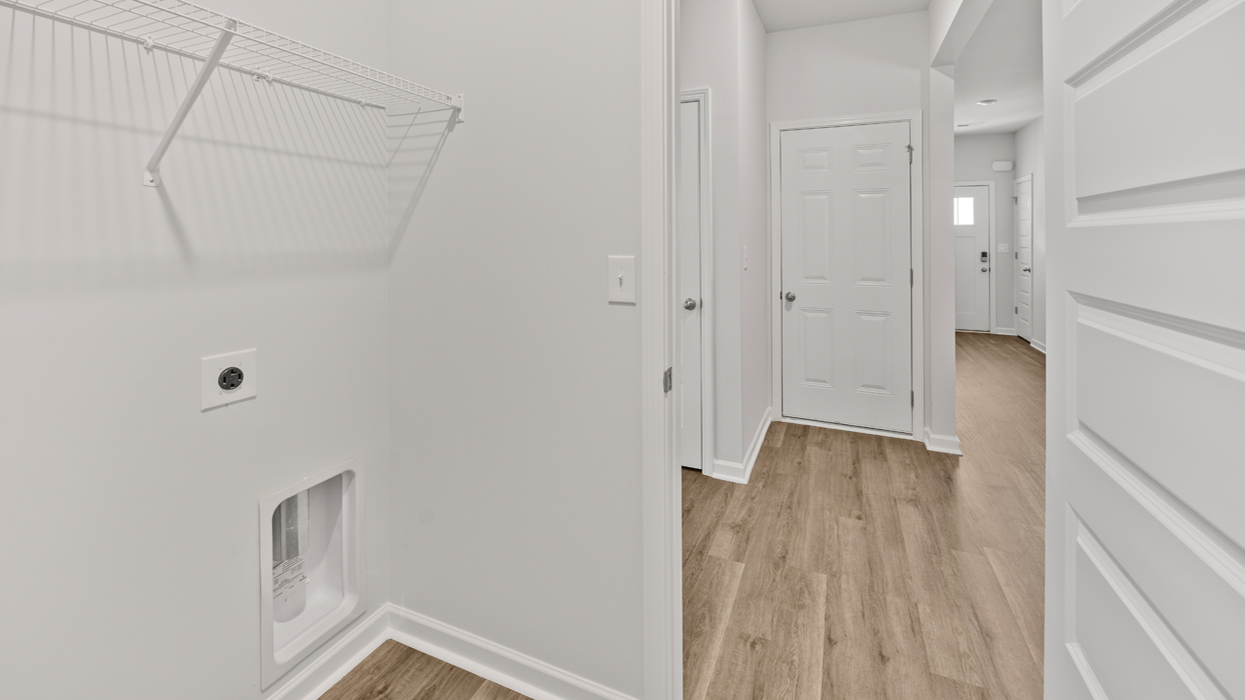 Laundry room with shelving and appliance connections.