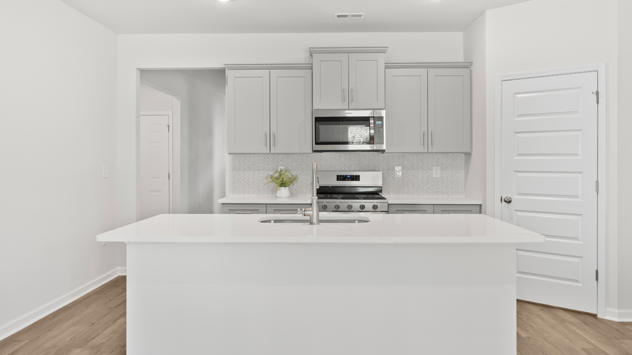 Modern kitchen with shaker cabinets, tile backsplash, quartz counters, corner pantry, and large center island.