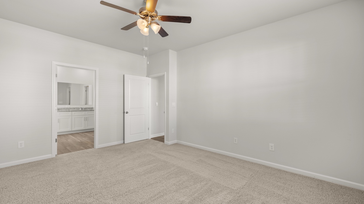 Primary bedroom with ceiling fan located just off of living room on main floor