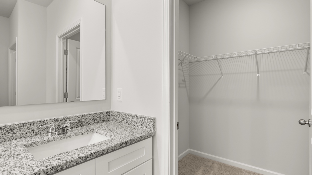 Primary bath on main level with double vanity, garden tub, shower with glass door, and large closet