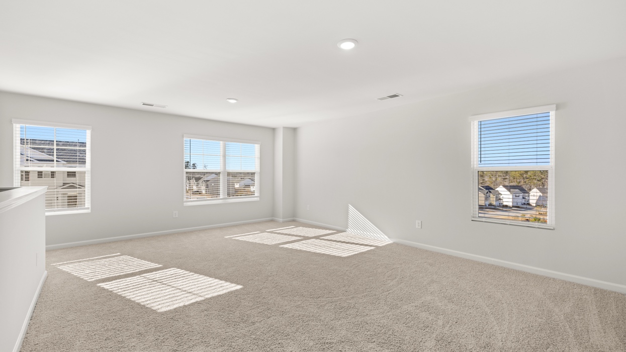 Expansive carpeted loft upstairs with half wall and tons of natural light