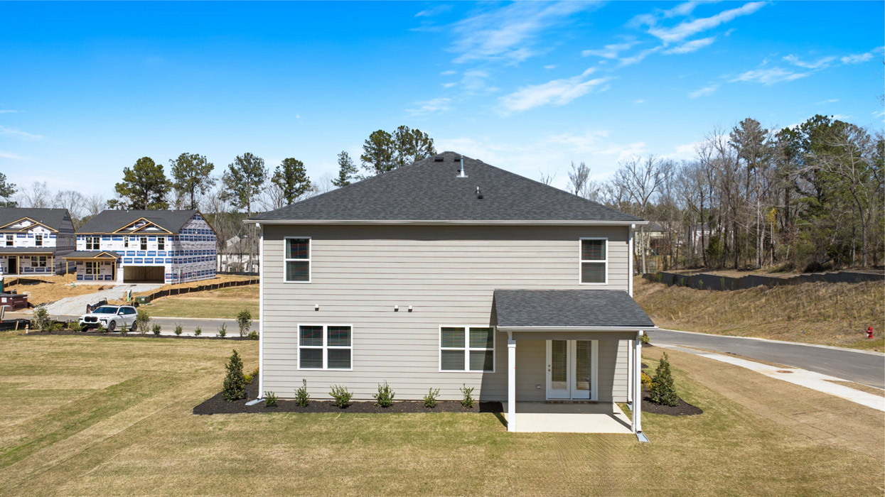 Rear of two story home with large covered back porch overlooking back lawn