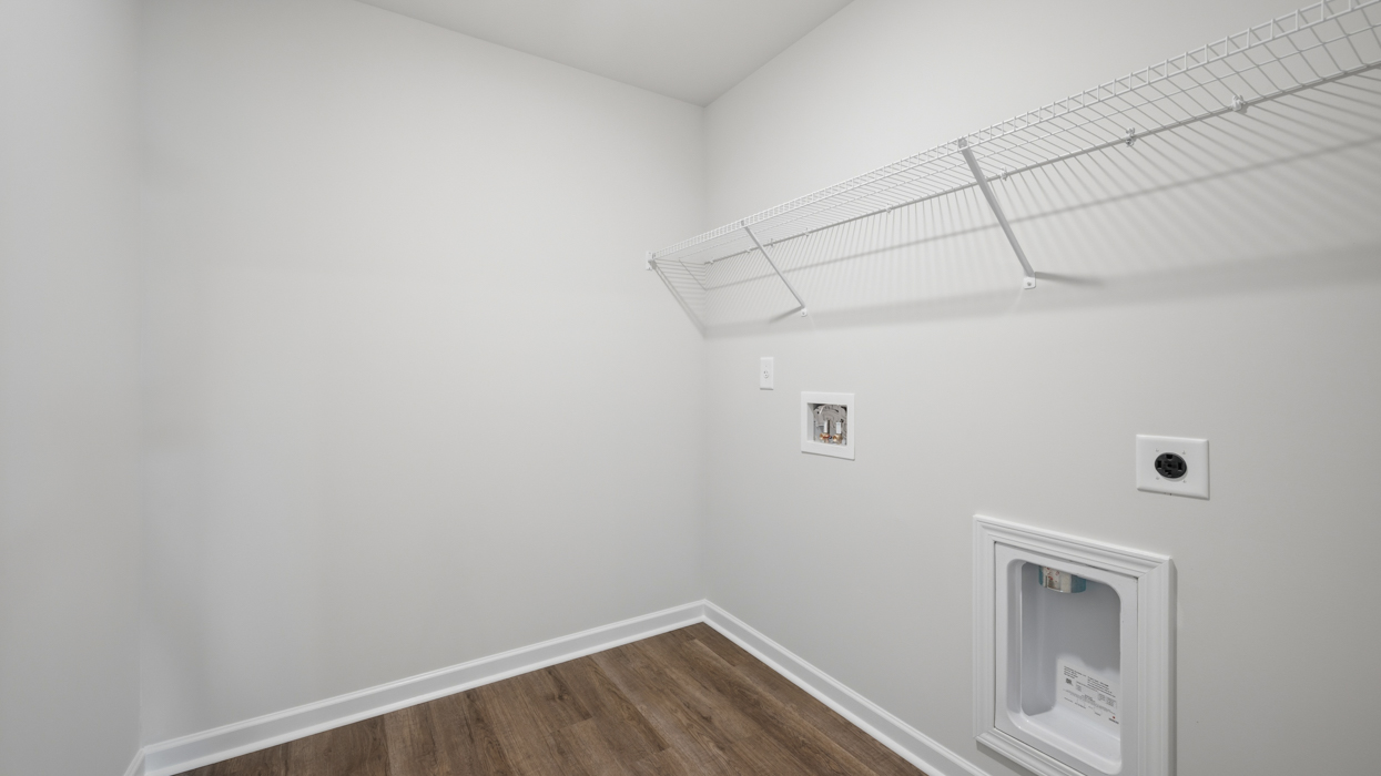 Laundry room upstairs with appliance connections and shelving above.