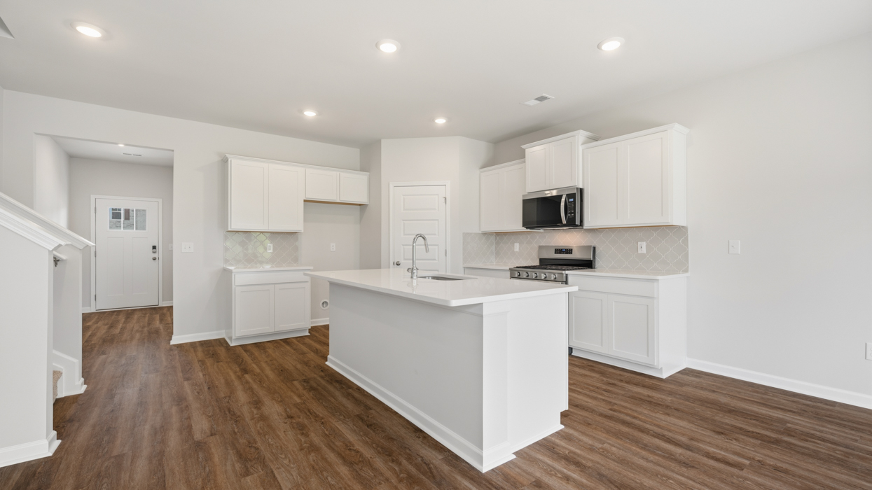 Modern kitchen with quartz countertops, tile backsplash, stainless appliances, and large center island with bar countertop
