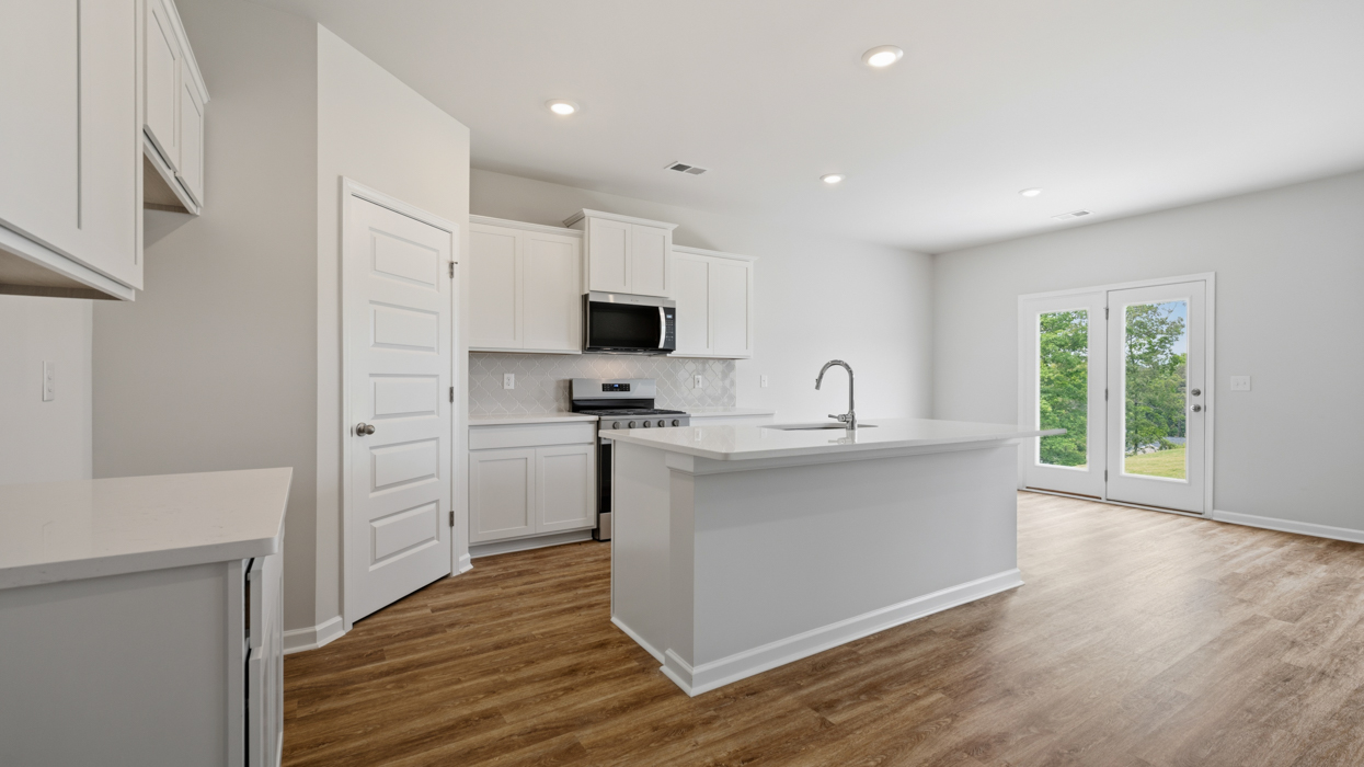 Modern kitchen with quartz countertops, tile backsplash, stainless appliances, and large center island with bar countertop
