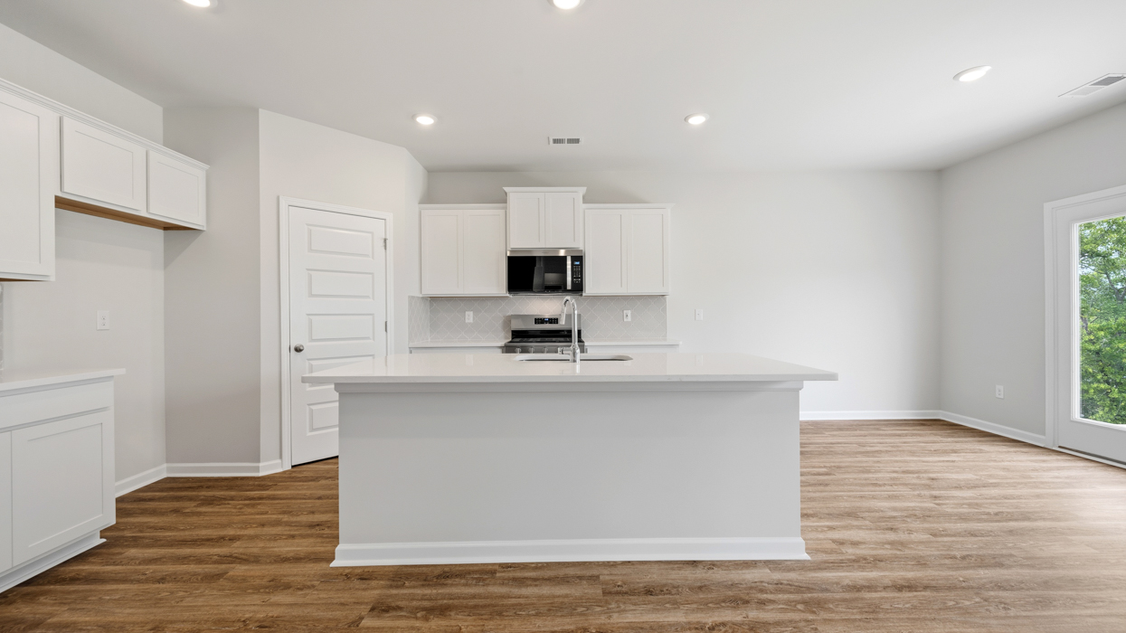 Modern kitchen with quartz countertops, tile backsplash, stainless appliances, and large center island with bar countertop