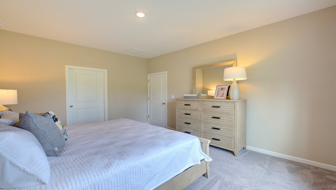 Carpeted primary bedroom with large windows