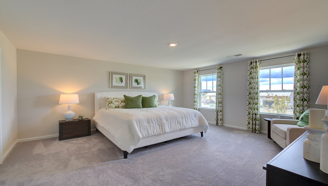 Carpeted primary bedroom with large windows