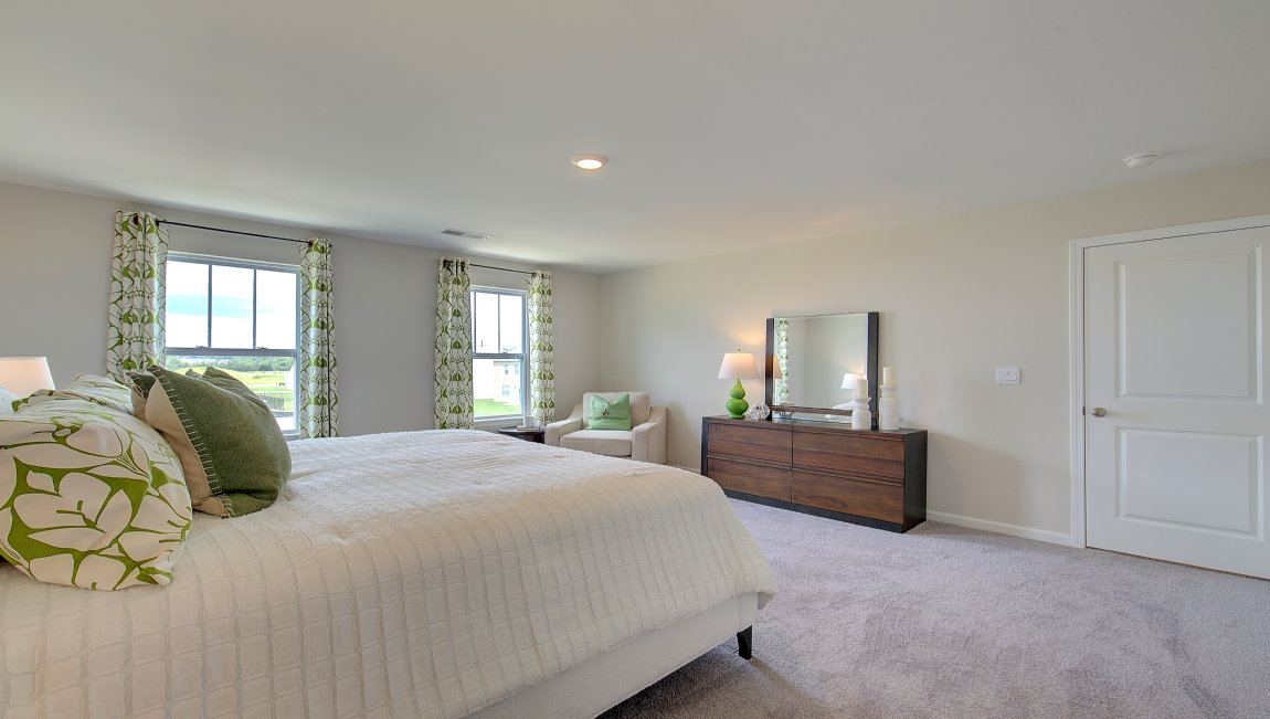 Carpeted primary bedroom with large windows