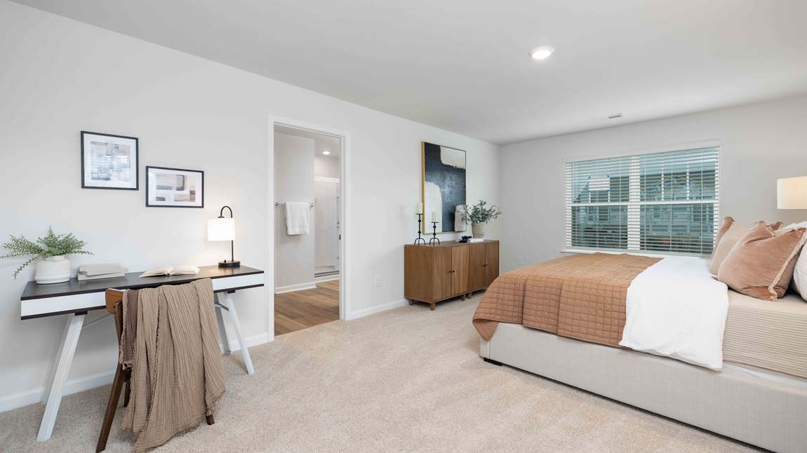 Carpeted primary bedroom with large windows