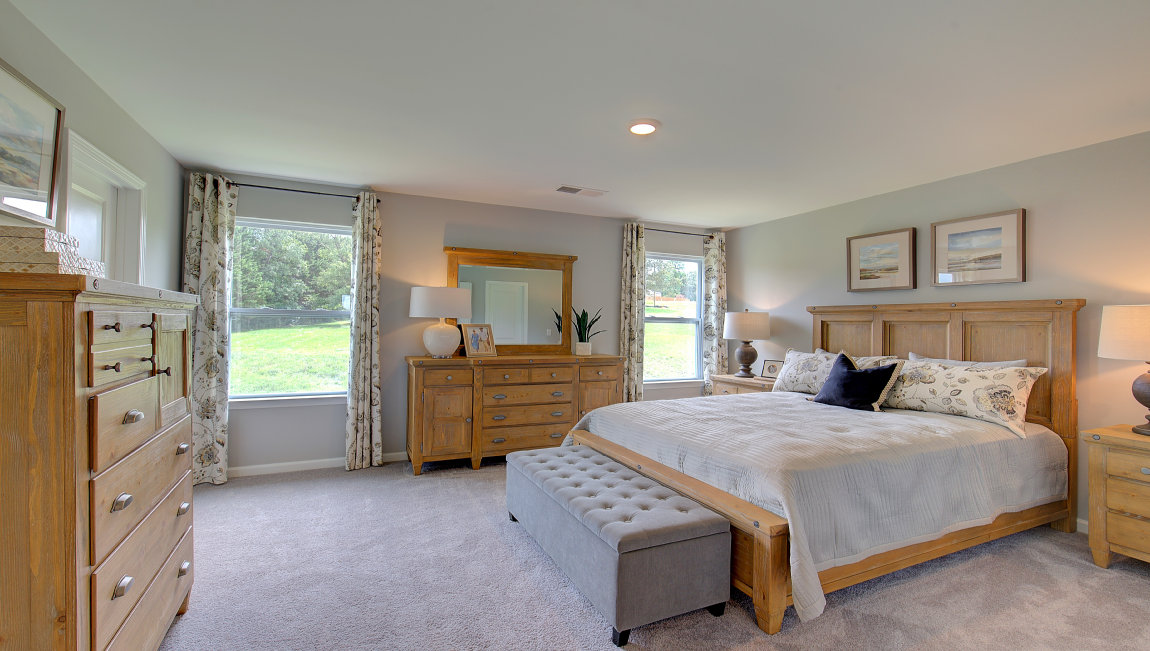 Carpeted primary bedroom with two small windows