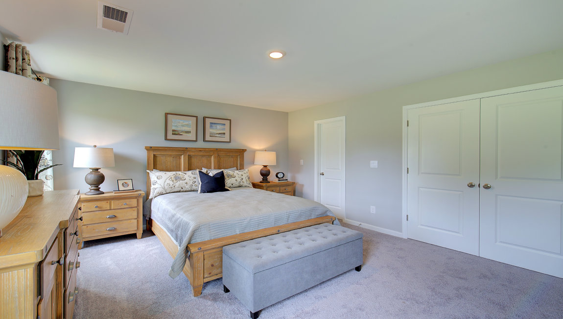 Carpeted primary bedroom with two small windows