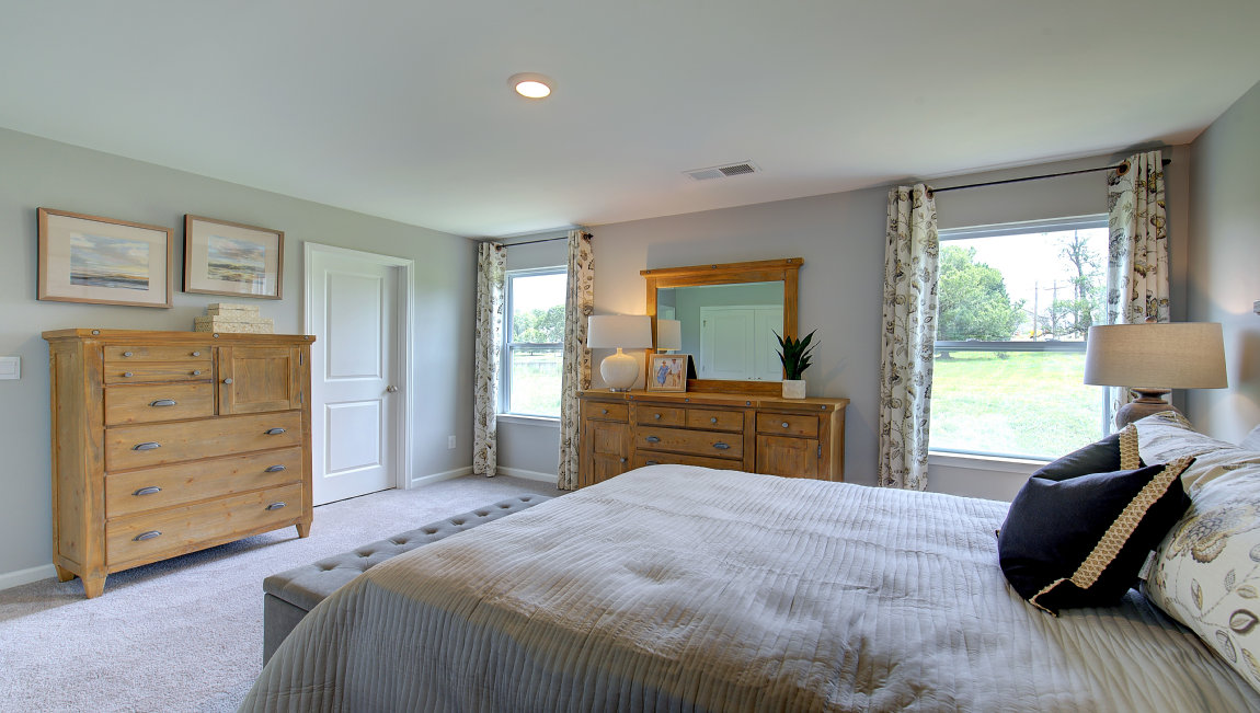 Carpeted primary bedroom with two small windows