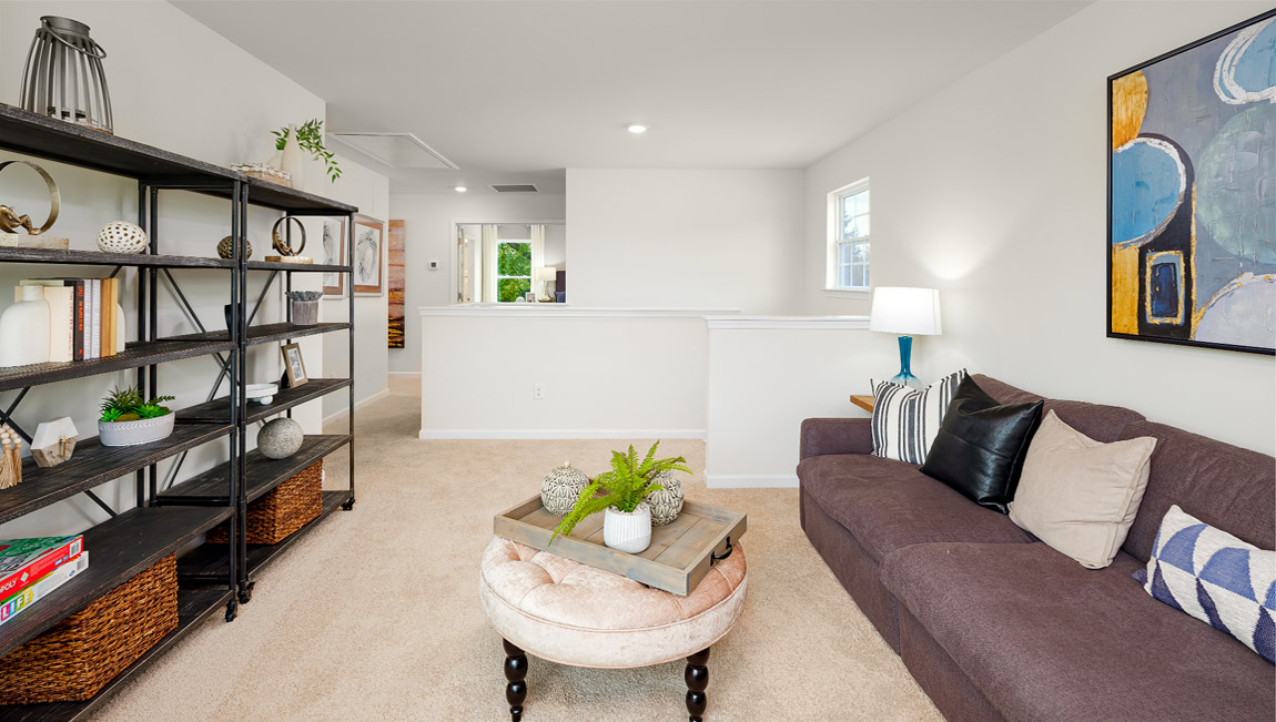 Carpeted loft area with windows