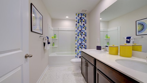 Bathroom with double sink vanity, brown cabinets and bathtub shower combination