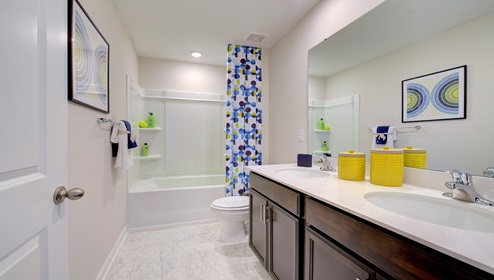 Bathroom with double sink vanity, brown cabinets and bathtub shower combination