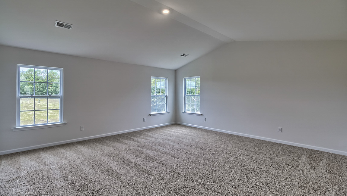 Carpeted primary bedroom with large windows