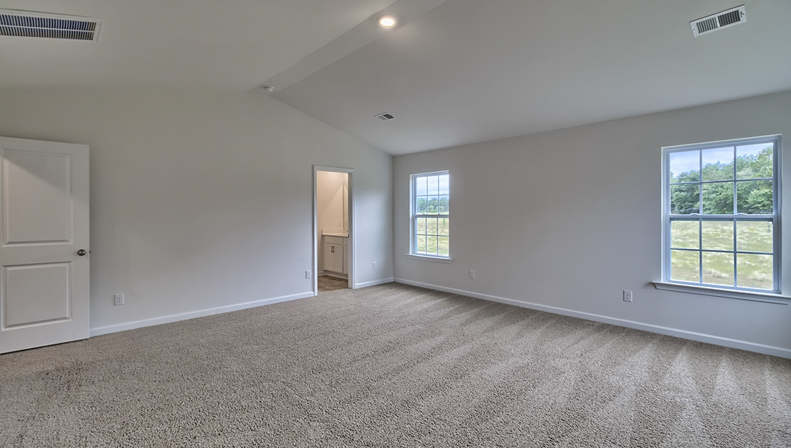 Carpeted primary bedroom with large windows