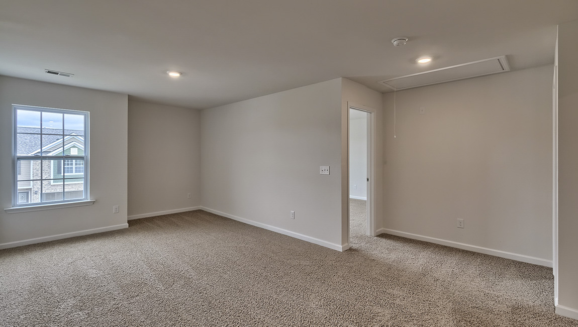 Carpeted loft area with windows