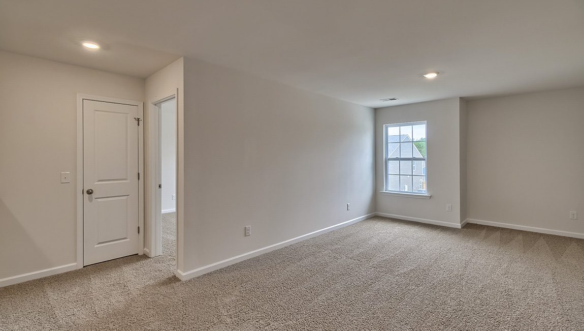 Carpeted loft area with windows