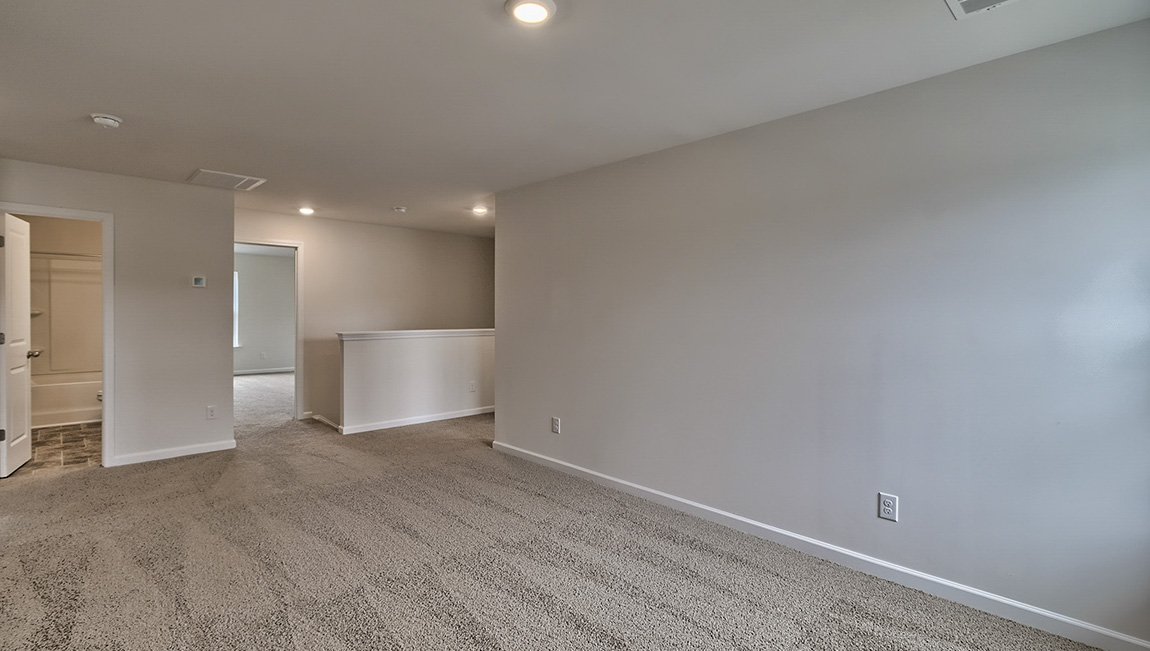 Carpeted loft area with windows