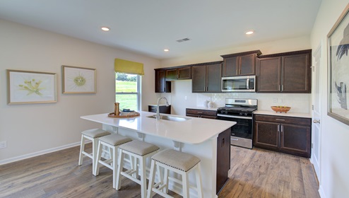 Kitchen and island with brown cabinets, white countertops, and stainless steel appliances