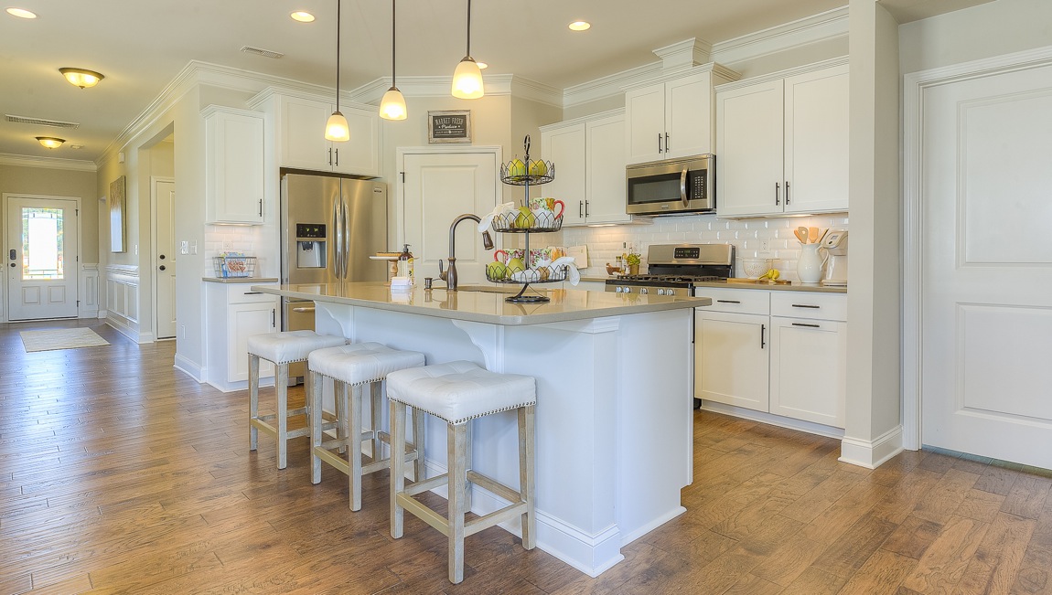 Kitchen and island with wood floors, white cabinets, breakfast area at island bar, and stainless steel appliances