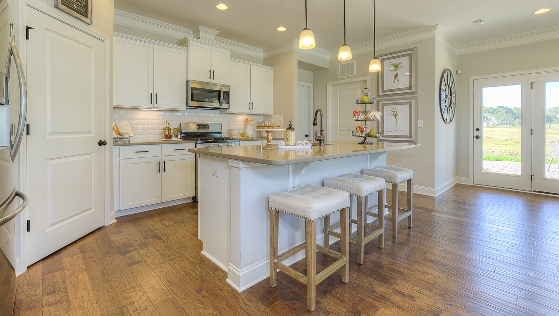 Kitchen and island with wood floors, white cabinets, breakfast area at island bar, and stainless steel appliances