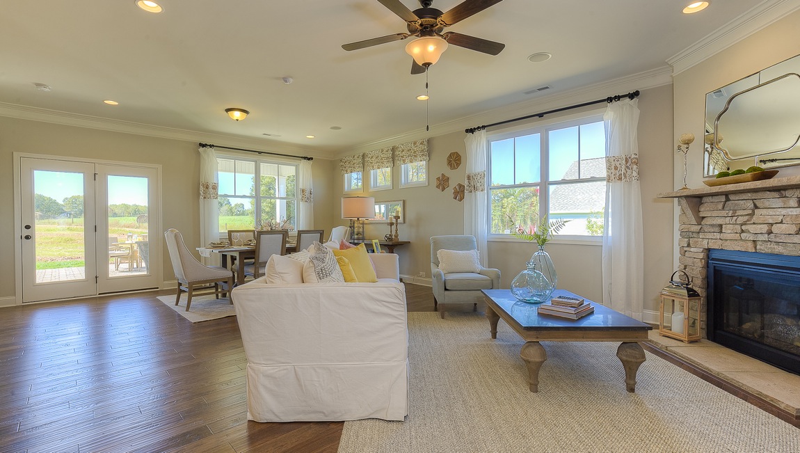 Open family room in view of dining room, with wood floors, large window and fireplace