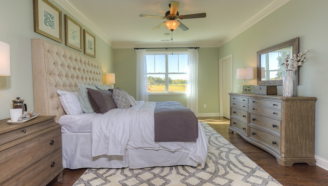Primary bedroom with wood floors, and large window