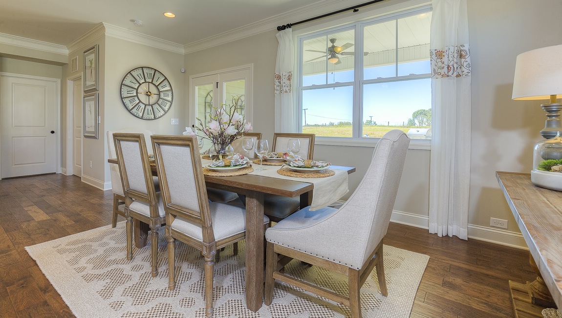 Dining room with wood floors, large windows, and back door to patio