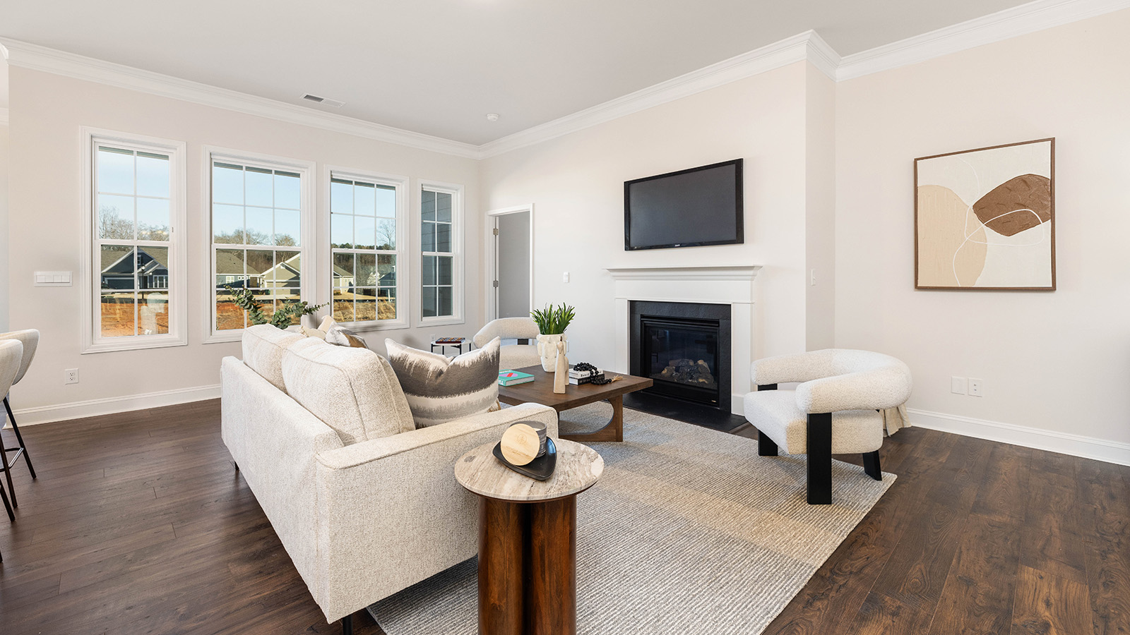 Open living room with wood floors, three windows, and fireplace
