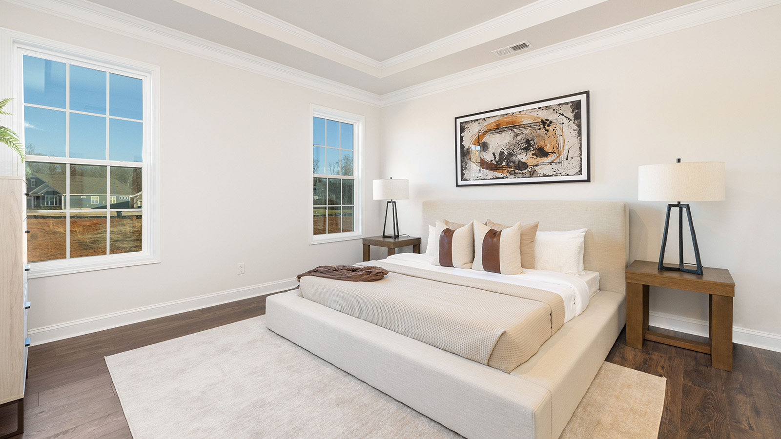 Primary bedroom with wood floors, and two large windows
