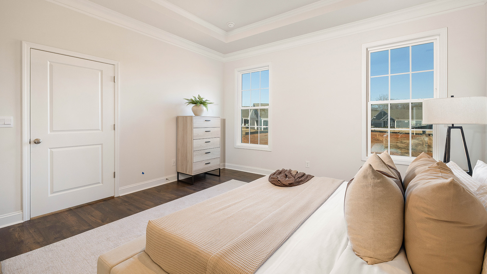 Primary bedroom with wood floors, and two large windows