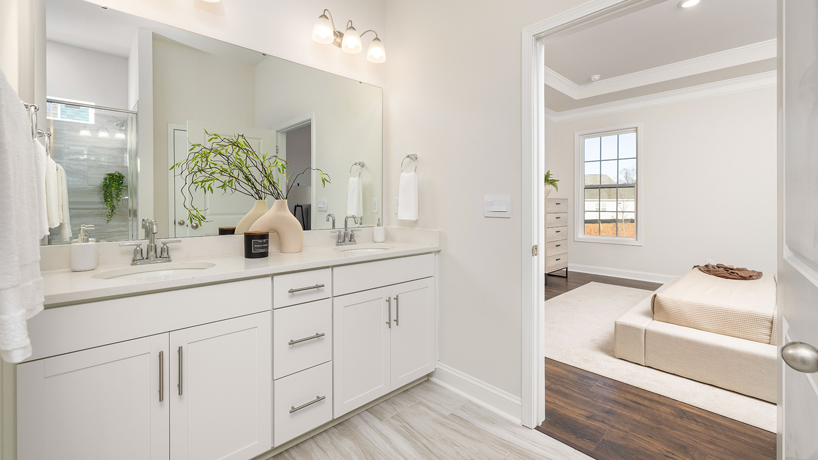 Primary bathroom with double sinks, white cabinets
